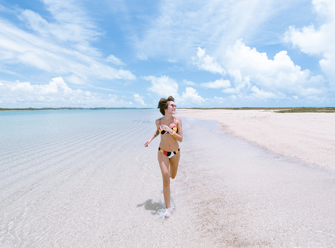 Mulher correndo feliz na areia da Croa de Sao Bento