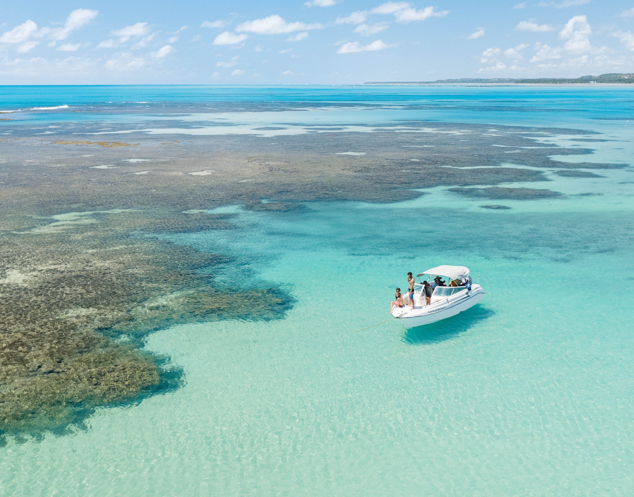 foto aérea de uma lancha parada perto dos corais das piscinas naturais de japaratinga