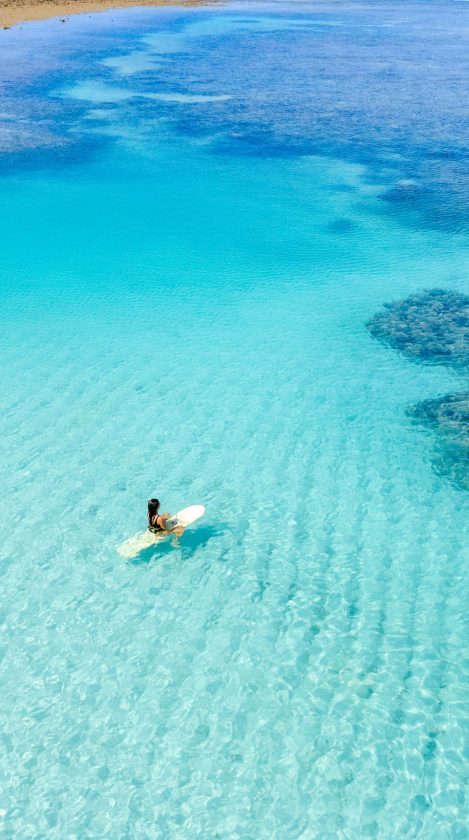 uma mulher em cima de uma prancha nas piscinas naturais de japaratinga