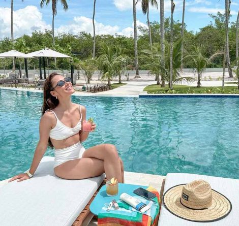 Com drink na mão e óculos escuros, hóspede aproveita o dia de sol na piscina do Japaratinga Lounge Resort, um Resort All Inclusive Premium em Alagoas.