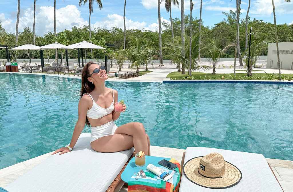 Com drink na mão e óculos escuros, hóspede aproveita o dia de sol na piscina do Japaratinga Lounge Resort, um Resort All Inclusive Premium em Alagoas.