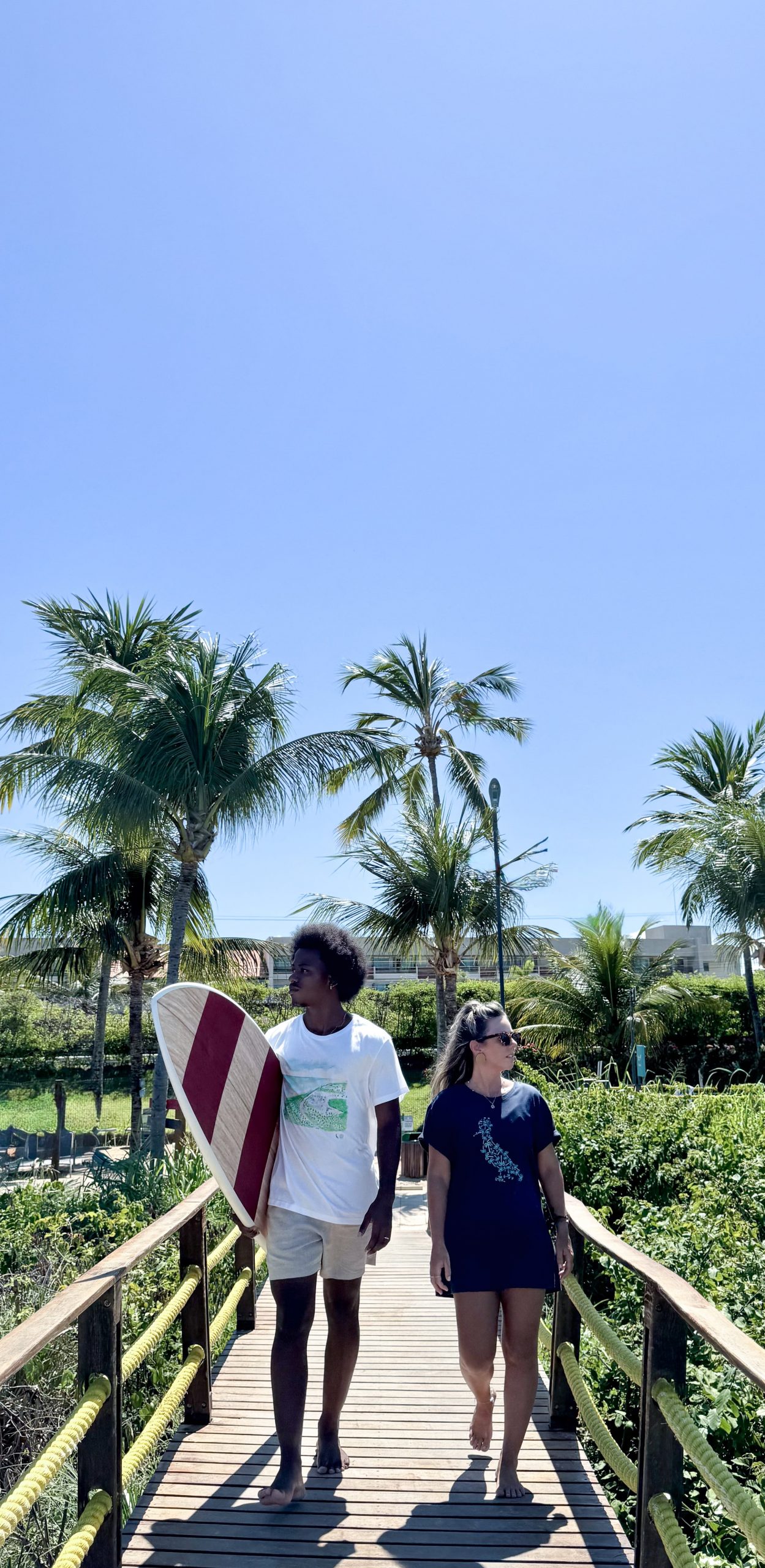 Casal vestindo short e camiseta da marca Reserva, em parceria com o Japaratinga Lounge Resort.