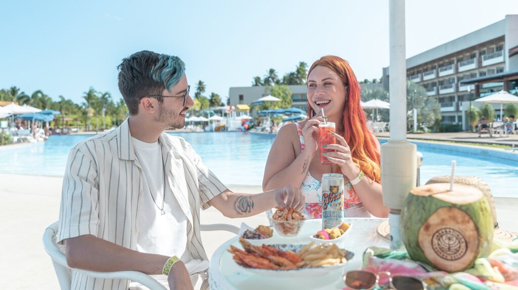 Casal aproveitando a diária com oferta All Inclusive Premium à beira da piscina do Japaratinga Lounge Resort.