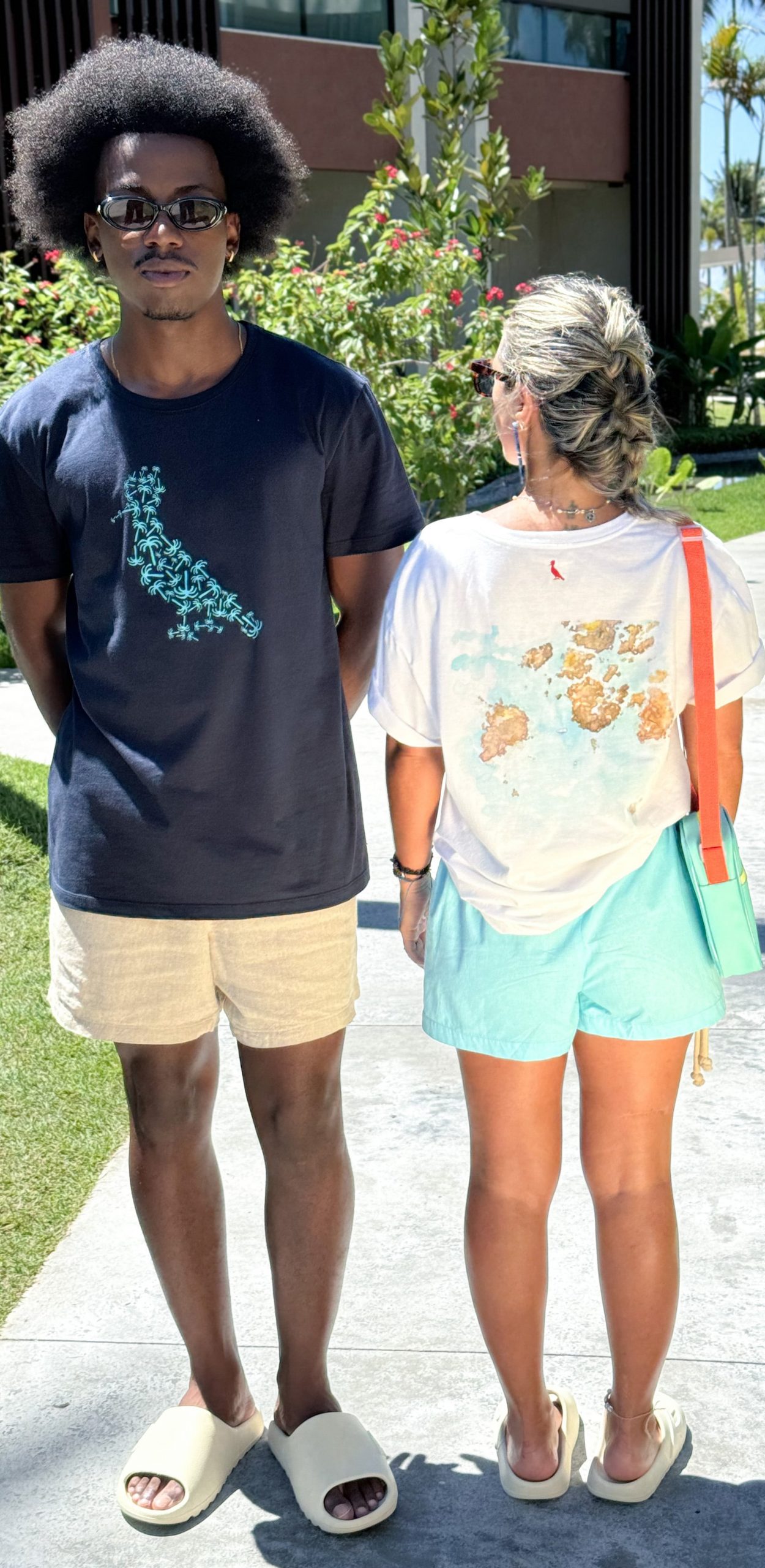 Casal vestindo short e camiseta da marca Reserva, em parceria com o Japaratinga Lounge Resort.