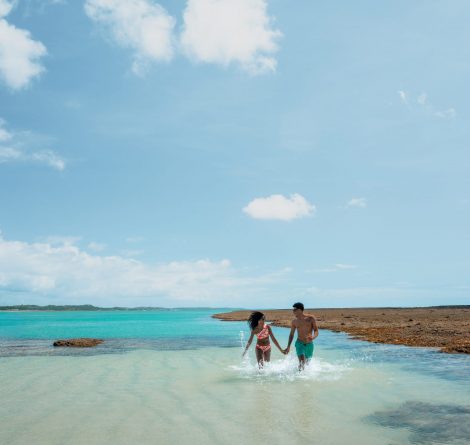 Casal caminha nas águas cristalinas entre recifes de corais das piscinas naturais de Japaratinga.