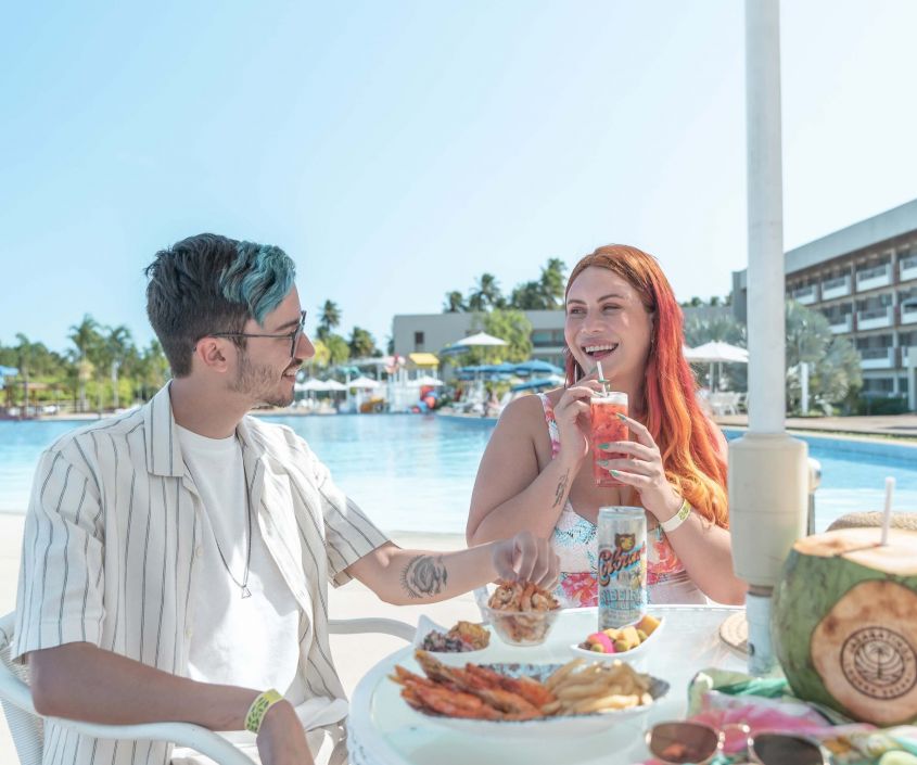 Casal se divertindo em almoço à beira da piscina no resort all inclusive.