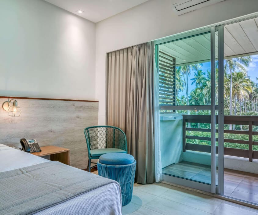 Cadeira com apoio para os pés e varanda com vista para mangue.