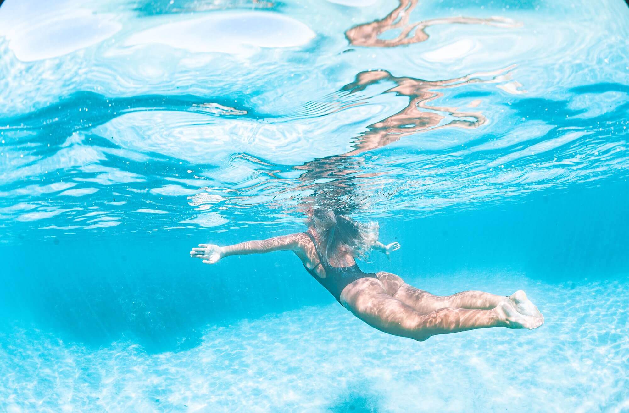 Imagem submersa de mulher mergulhando.