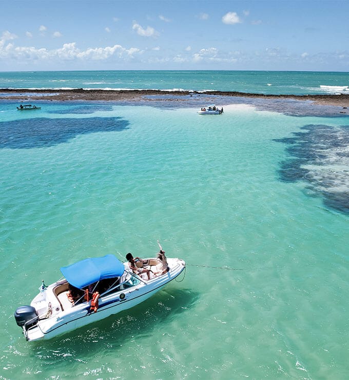 Vista aérea de homem e mulher na popa da lancha nas piscinas naturais.
