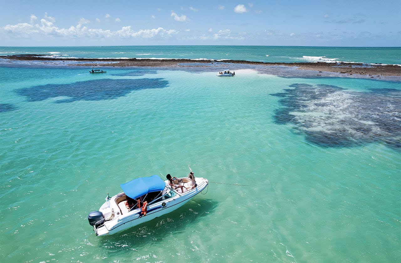 Vista aérea de homem e mulher na popa da lancha nas piscinas naturais.