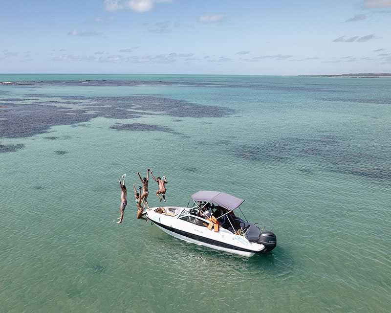 Imagem mostra quatro amigos pulando no mar das piscinas naturais de Japaratinga.