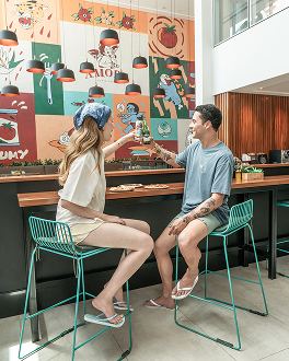Casal brindando e comendo pizza na Amore Forneria, no Japaratinga Lounge Resort.