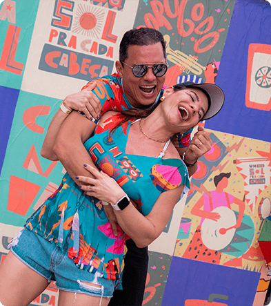 Casal sorrindo e vestindo abadá do bloco Um Sol pra Cada Cabeça d Japaratinga Lounge Resort