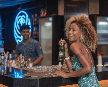 Imagem mostrando mulher sorrindo no Pub Overdrive com cerveja na mão.