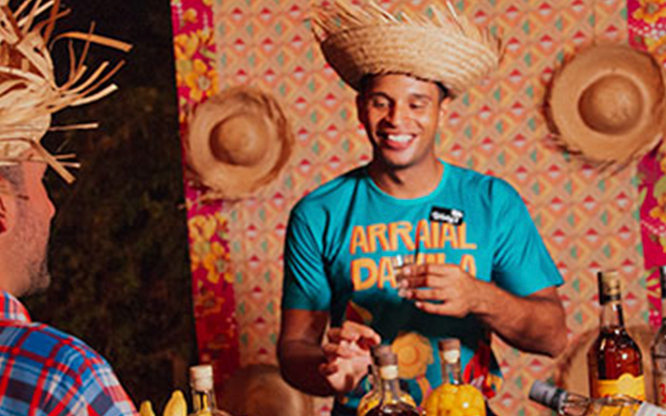 Barman servindo uma dose de cachaça nas festas juninas do japaratinga Lounge Resort, o Arraial da Vila.