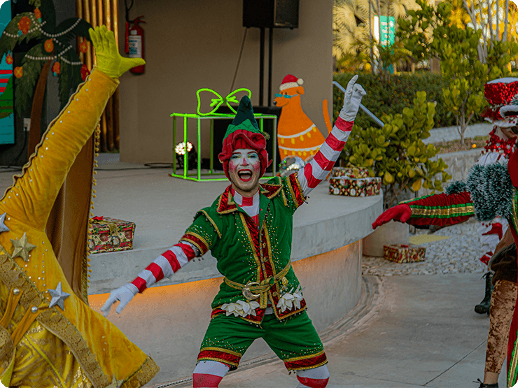 A Praça dos Coqueiros com o palco no fundo decorado com um telão digital de natal. E personagens natalinos fazendo uma apresentação.