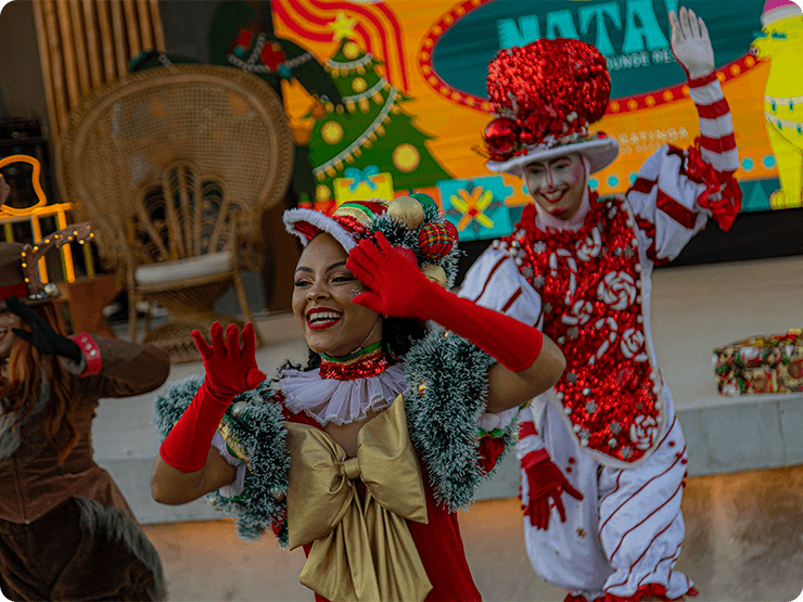 Personagens de natal fazendo apresentação na Praça dos Coqueiros, com o palco no fundo decorado com um telão digital de natal.