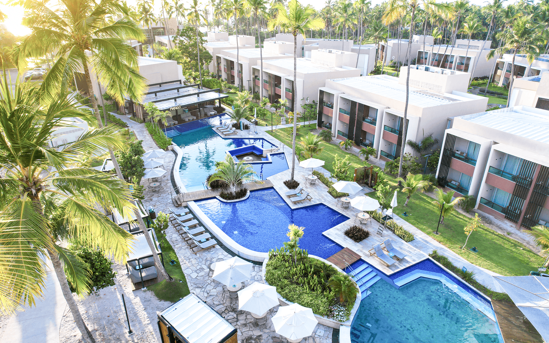 Vista das Gardens e áreas de lazer do Japaratinga Lounge Resort cercadas por jardins tropicais em dia ensolarado.