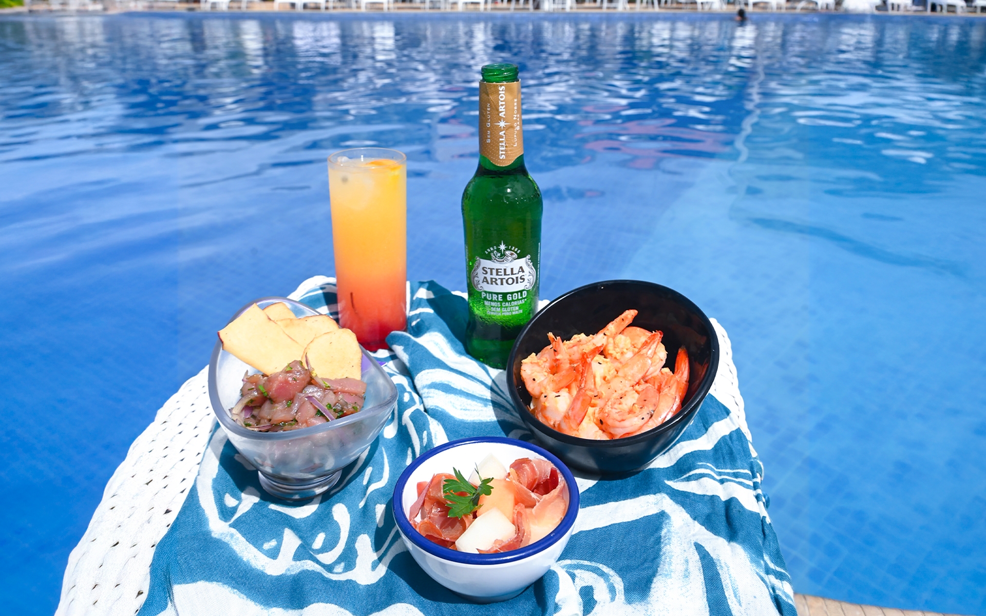 all-inclusive-premium-24h-dia Petiscos de frutos do mar, ceviche, coquetel tropical e cerveja Stella Artois Pure Gold servidos à beira da piscina azul no Japaratinga Lounge Resort.