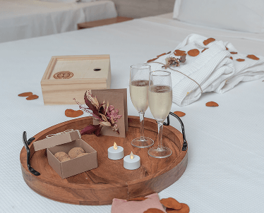 Casal relaxando em uma banheira de hidromassagem no spa. Ambiente com plantas, velas acesas e a espuma na banheira.